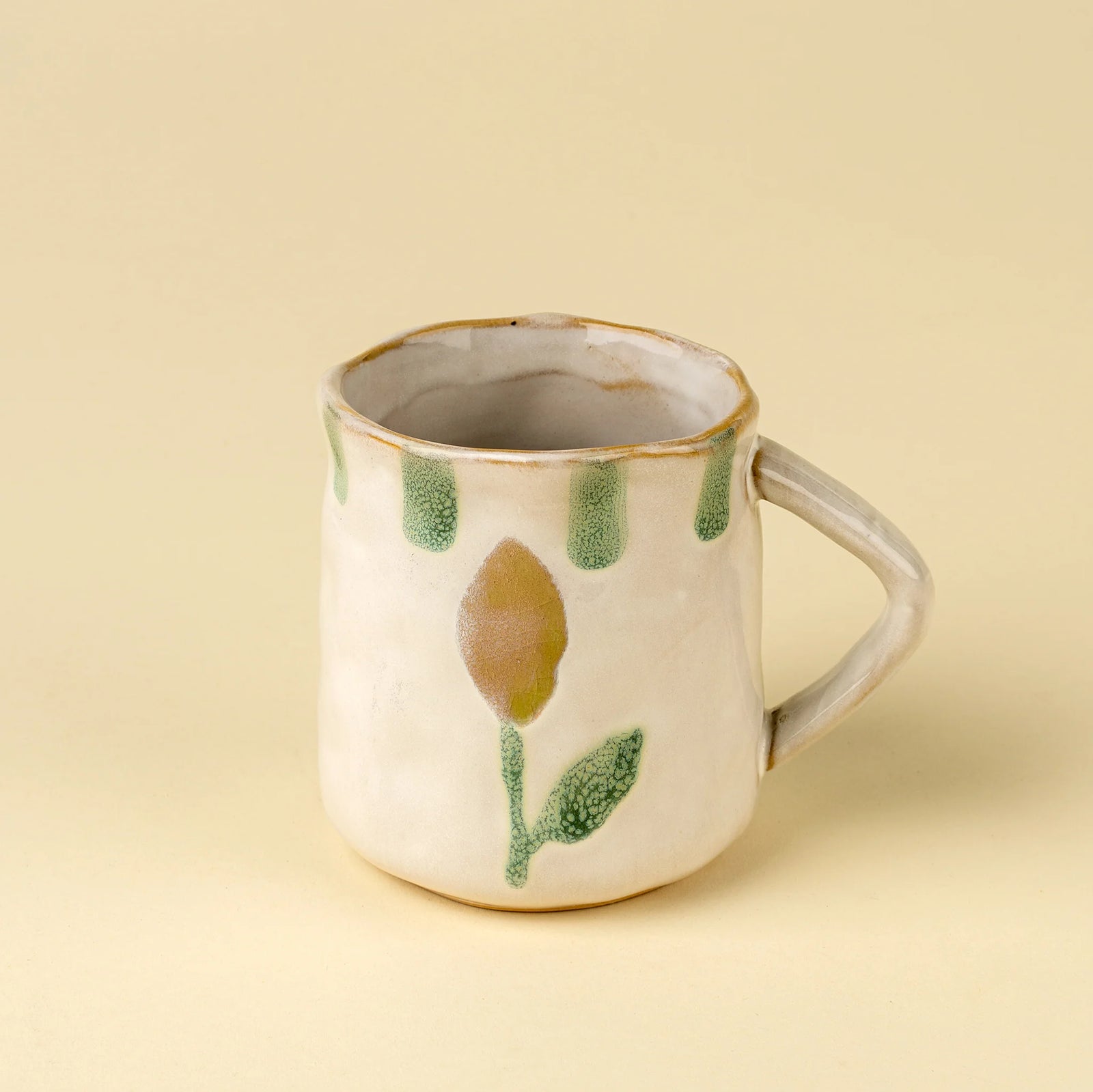 Hand painted stoneware mug with lemon and leaf design on a beige background. 