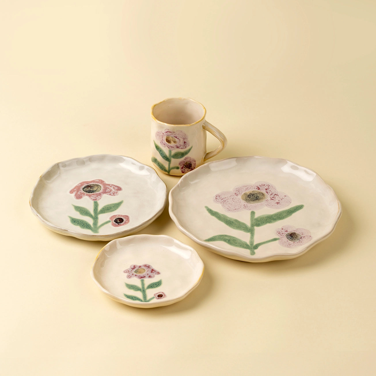 Ceramic tableware set with floral Aster bloom designs on a beige background. Mug, dinner plate, salad plate, and appetizer plate. 