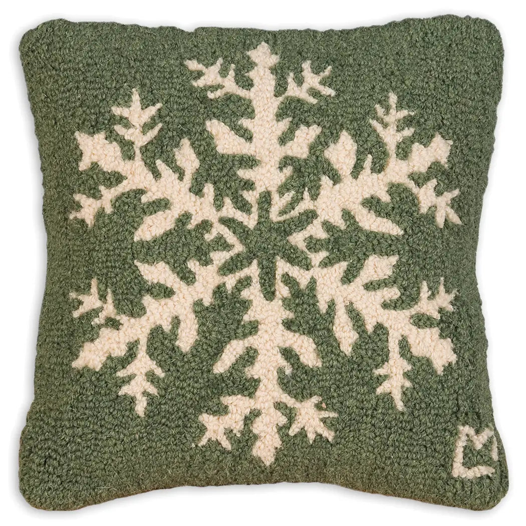 A square wool pillow featuring a large cream-colored snowflake design on an olive green textured background.