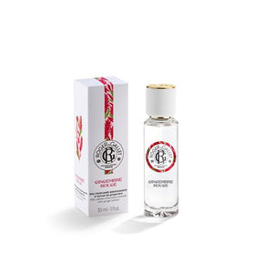 A clear glass bottle of GIngembre Rouge Eau de Parfum from Roger & Gallet with a gold cap, standing next to its white packaging box decorated with red and green ginger motifs, on a clean white background.