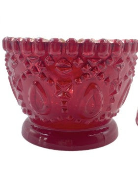 A vintage red mercury glass tea light votive with a textured, embossed diamond and floral pattern and a fluted rim, set against a plain white background.
