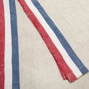 Close-up of linen fabric with red, white, and blue stripes on a beige background. 