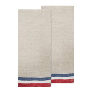 Two natural linen and cotton tea towels with red, white, and blue striped edge detailing on a white background. 