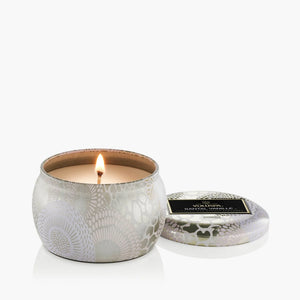 4 ounce tin candle in scent Santal Vanilla with wick lit. Voluspa. 