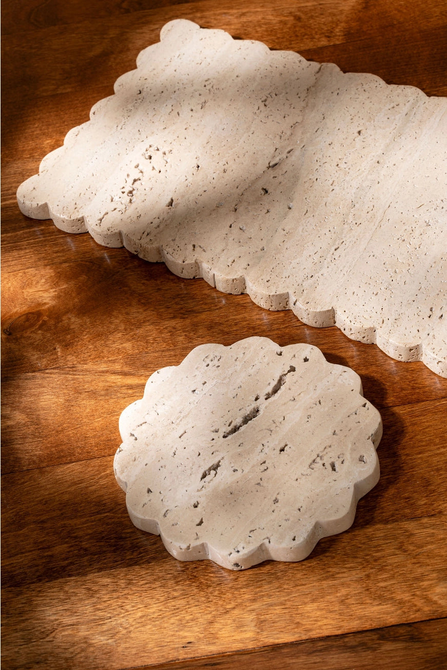 Decorative travertine stone scalloped trays on a wooden surface.