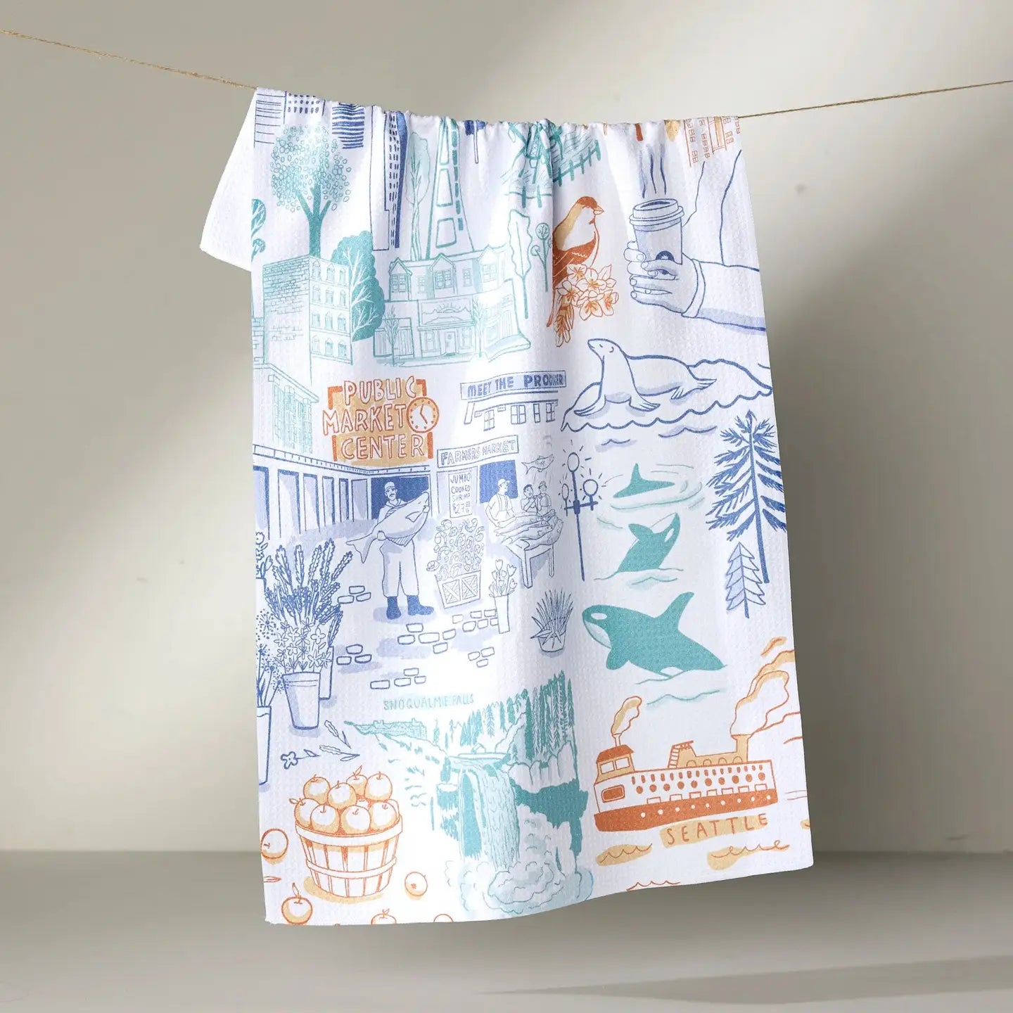 Tea Towel with a colorful pattern of Seattle-themed buildings, trees, and animals on a plain background