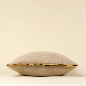 Beige belgian linen pillow with sunflower yellow selvage trim on a beige background from side profile view. 