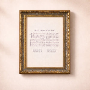 Framed sheet music for 'Silent Night, Holy Night' on a beige wall.
