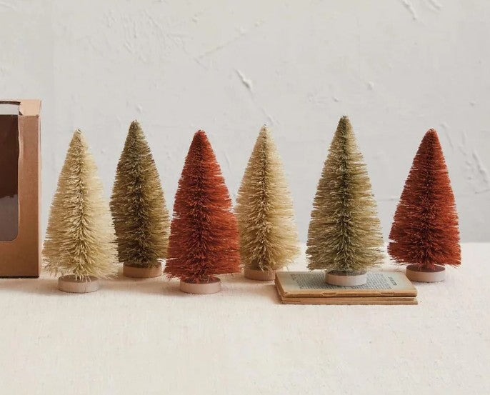 Set of small bottlebrush trees in various colors on a white surface with a neutral background