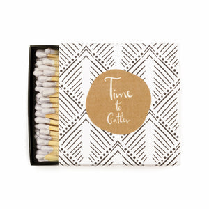 white match box with black pattern and gold circle with saying "time to gather"