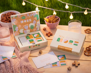 Tell Me More Family Edition on a wood table with game pieces and snacks. 