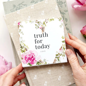 Hand holding daily devotional cards titled "Truth for today love" with floral design on a textured surface. Emily Lex Studios.