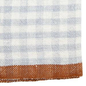 Close-up of a linen fabric napkin with a light blue gingham pattern transitioning to a solid brown color.