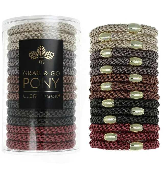 A clear cylindrical container holding multiple braided ponytail hair ties, shown beside a stacked display of the same hair ties. The ponytails come in beige, brown, black, and burgundy, each accented with small metallic gold oval beads.