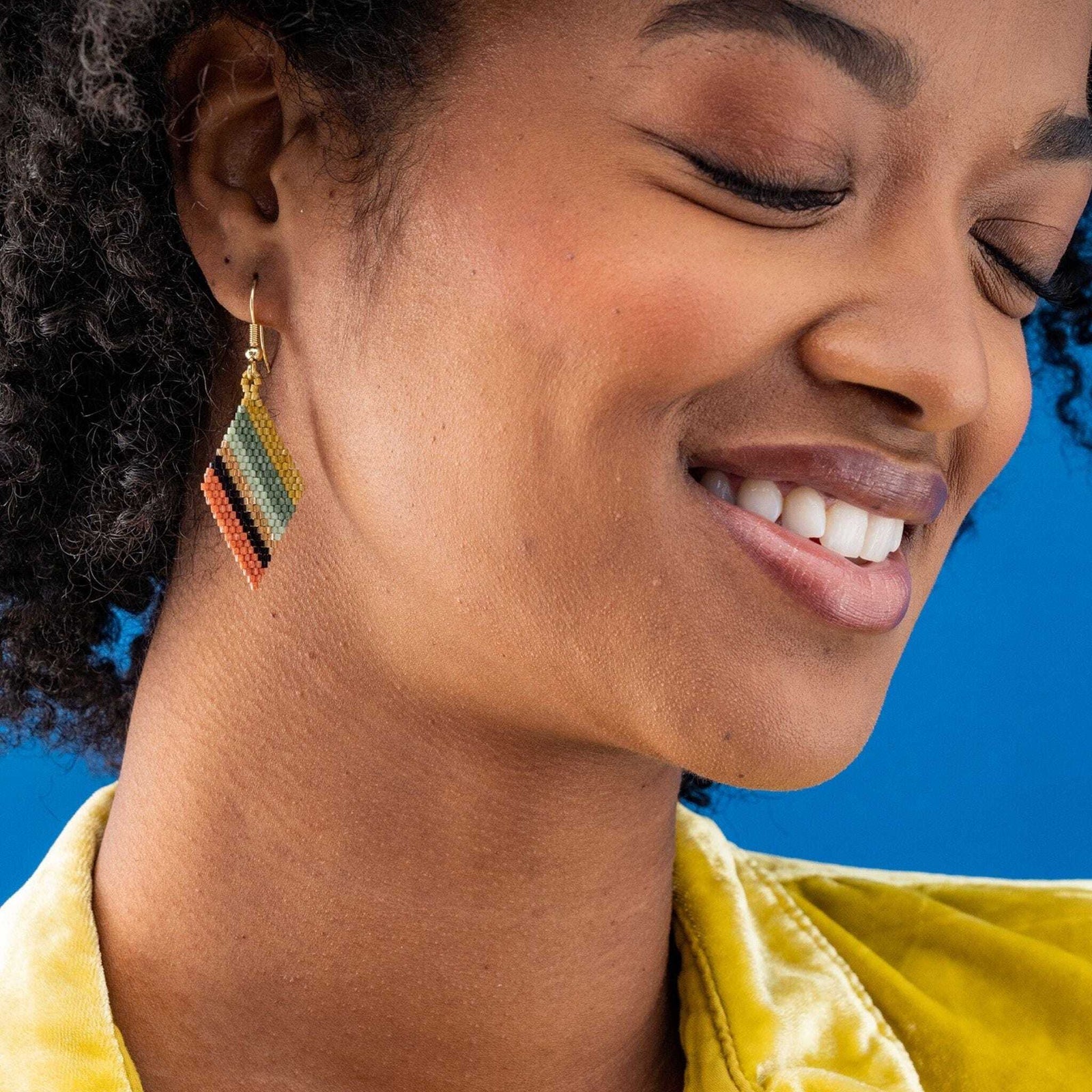 Model wearing multicolored angle striped beaded earrings. 